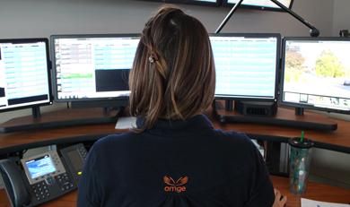 a photo of a female Communications Officer sitting in front of several computer screens