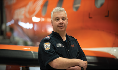 A paramedic in uniform standing in front of an orange plane
