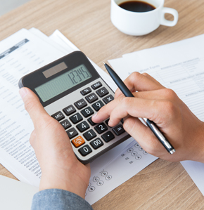 A hand holding a calculator over a sheet with financial information