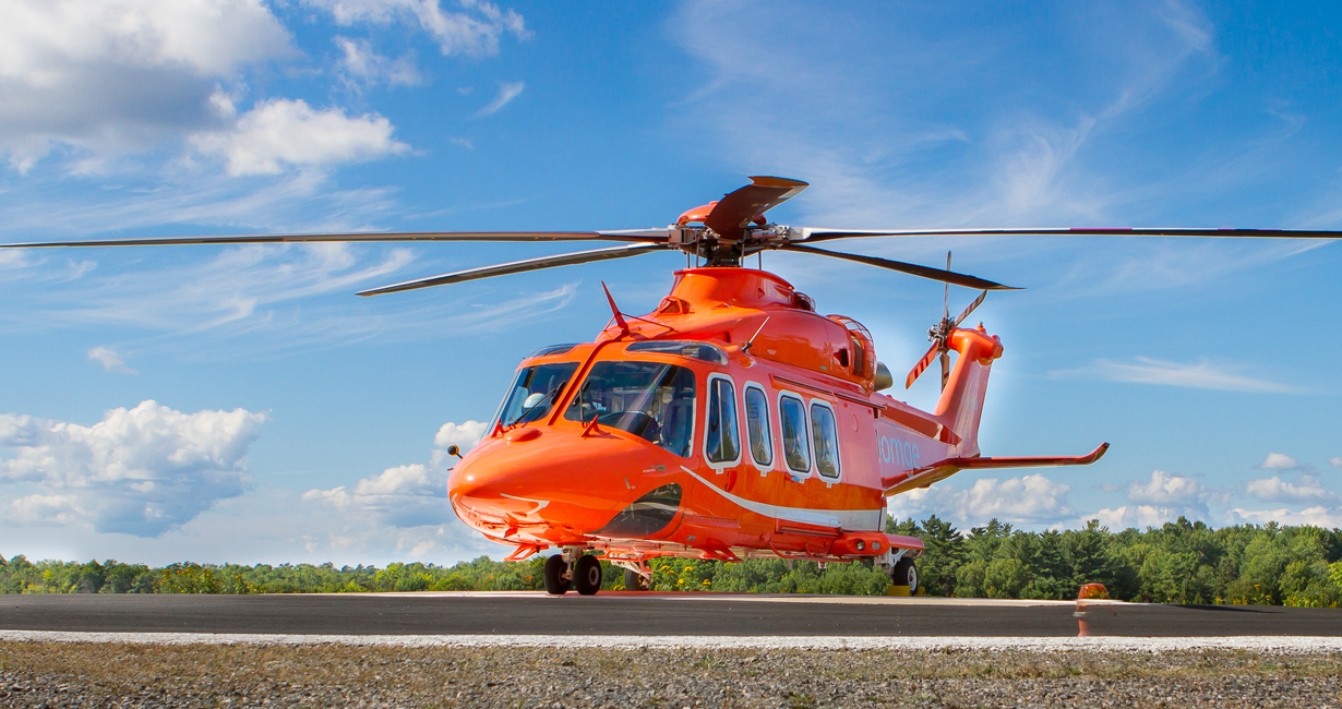 An Ornge Leonardo AW139 helicopter on a helipad with a blue sky in the background