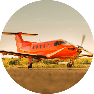 An Ornge Pilatus PC-12 airplane in front of an beautiful orange sunset sky