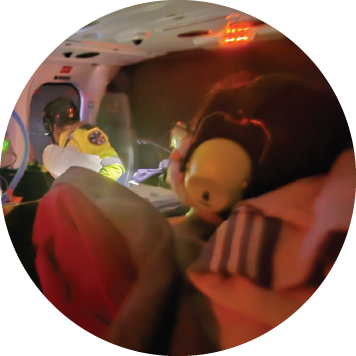 Medical crew caring for a patient inside an air ambulance with monitors and equipment illuminated.