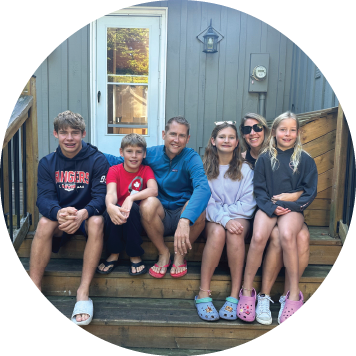 wo people wearing Toronto Blue Jays jerseys and caps pose in front of a photo of a baseball player, each holding up one finger.