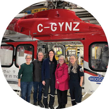 Medical crew caring for a patient inside an air ambulance with monitors and equipment illuminated.