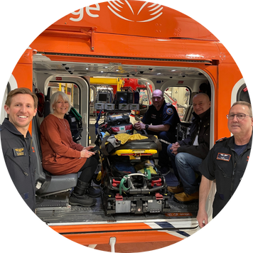 a group of people inside and in front of an orange helicopter