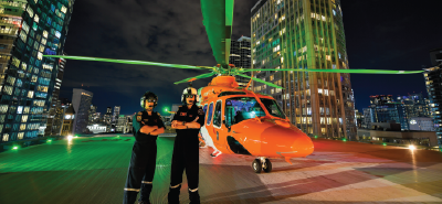 deux pilotes sur un héliport à côté d'un hélicoptère orange