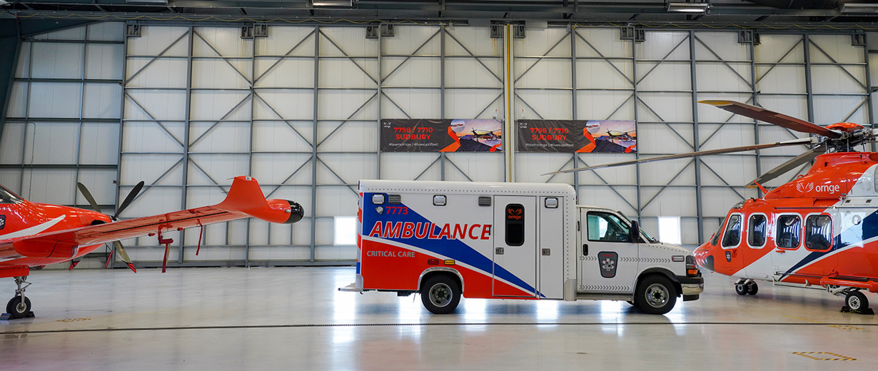 An Ornge PC 12 plane, AW139 helicopter and an ambulance are parked inside the Sudbury hangar.