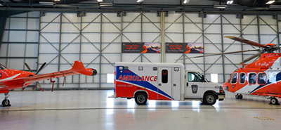 An Ornge PC 12 plane, AW139 helicopter and an ambulance are parked inside the Sudbury hangar.