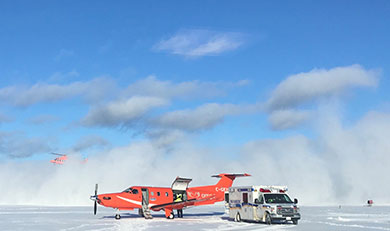 An Ornge fixed wing aircraft accepting a patient from Simcoe Paramedic Service and a helicopter landing in the background. 