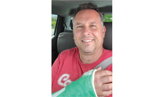 a man in a red t-shirt with a green cast on his arm