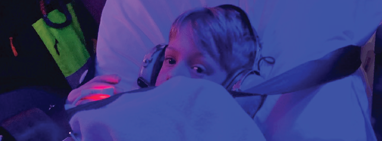 Patient secured on a stretcher with safety straps under blue and purple lighting inside a medical transport setting.