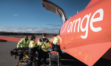 Paramedics transfer a patient to an orange Ornge air ambulance