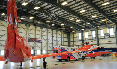 un avion orange à côté d'une ambulance et d'un hélicoptère orange à l'intérieur d'un hangar