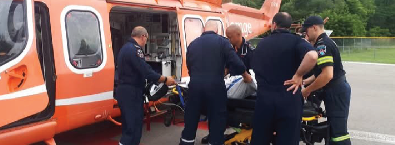 paramedics loading a patient into an orange helicopter