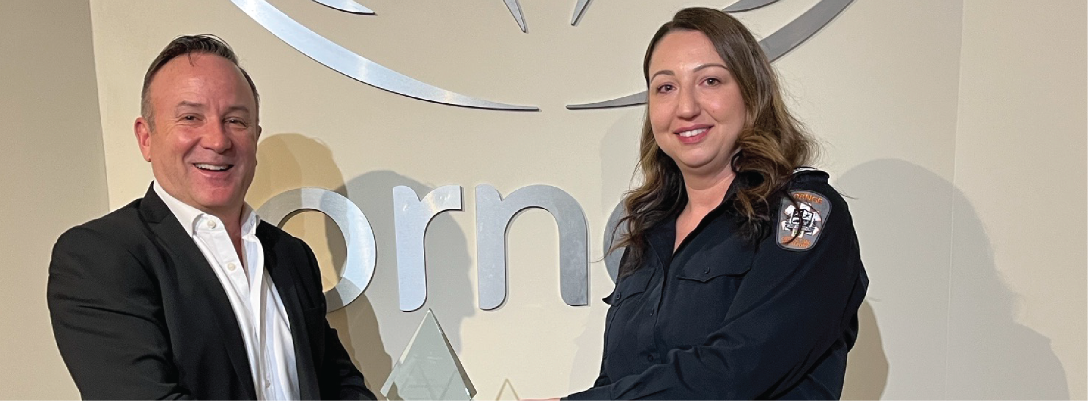 Two people holding an award together in front of an Ornge logo backdrop.