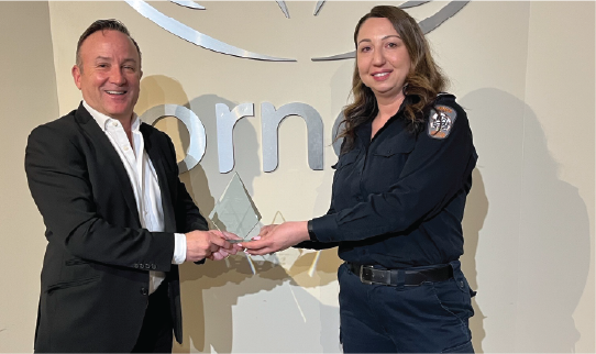Two people holding an award together in front of an Ornge logo backdrop.