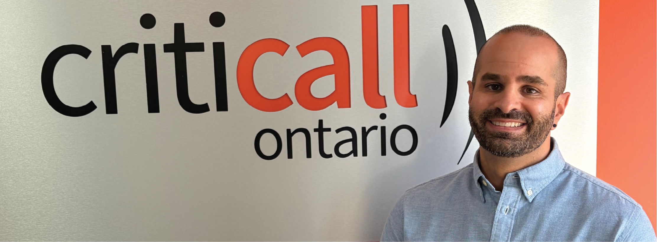 Une personne se tient à côté d'un panneau mural sur lequel on peut lire « CritiCall Call Ontario ».