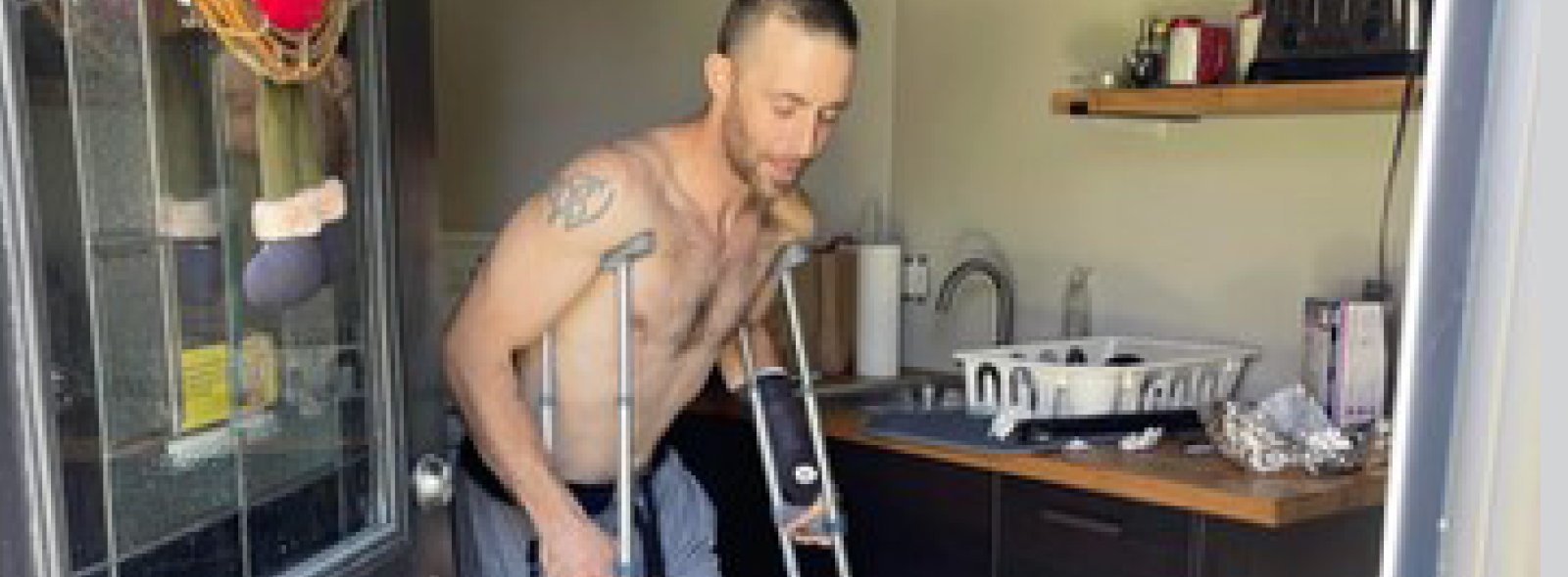 Scott walking in his home with crutches.