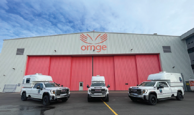Three EFRT vehicles parked in front of a hangar with large red doors and the Ornge logo