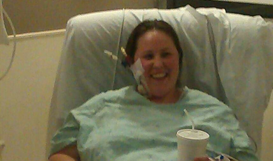 Annie Maynard laying down in a hospital bed with the blankets pulled up tightly around her face.