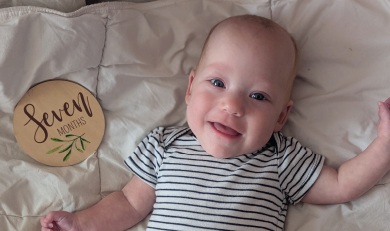 Baby Edith lying on a blanket smiling. 