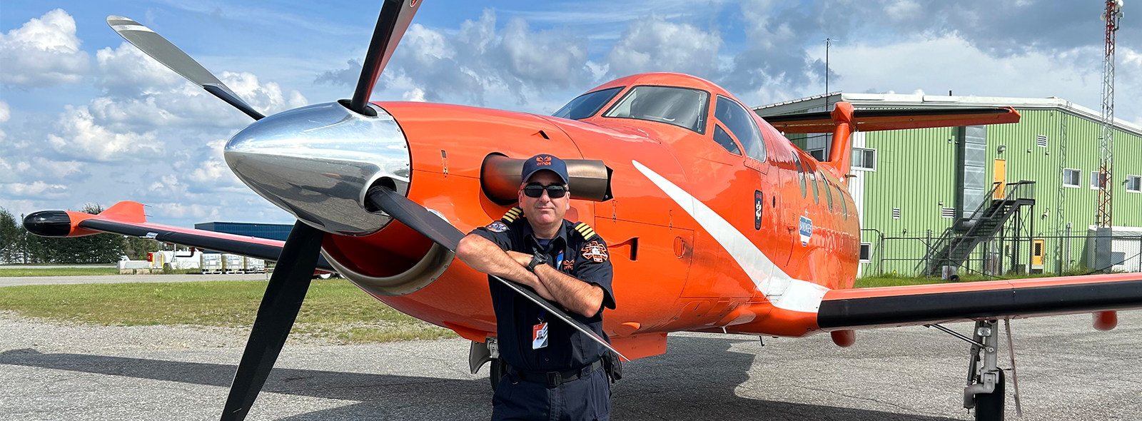 Une photo du capitaine Aaron Grubin appuyé sur l'hélice d'un avion d'Ornge