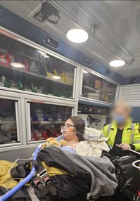 Paramedic attending to a patient on a stretcher inside an ambulance filled with medical equipment.