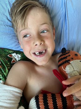 Child laying in bed holding a stuffed animal
