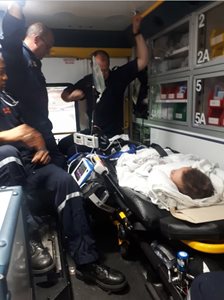 three paramedics in an ambulance with a patient